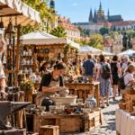 Tradiční řemeslný jarmark na historickém náměstí s ukázkami práce kováře, keramičky a řezbářky mezi prodejními stánky.